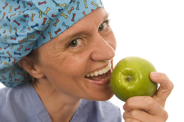 Улыбающаяся счастливая медсестра доктор ест зеленое яблоко — стоковое фото