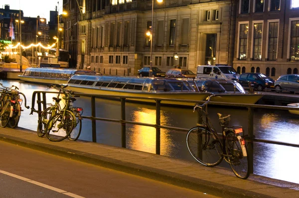 Лодки на канале с велосипедами ночь amsterdam Холланд — стоковое фото
