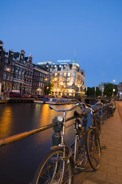 Amsterdam natt canal scen med cyklar och båtar — Stockfoto