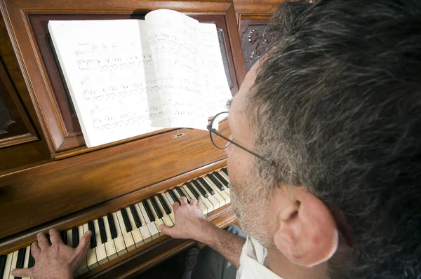 Старший мужчина среднего возраста играет на пианино — стоковое фото