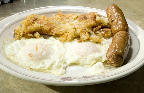 Fried eggs over easy pork sausages home fried potatoes breakfast — Stock Photo, Image