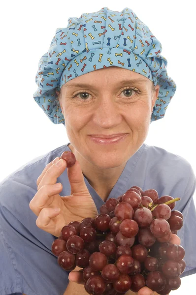 Enfermera promoviendo una dieta saludable con uvas de frutas frescas mientras weari —  Fotos de Stock