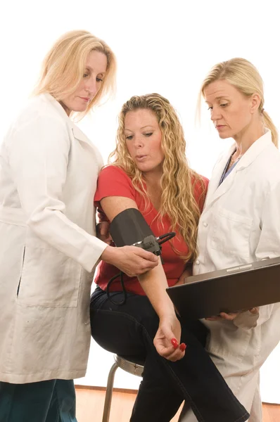Two doctors nurses in medical scrubs clothes with patient — Stock Photo, Image