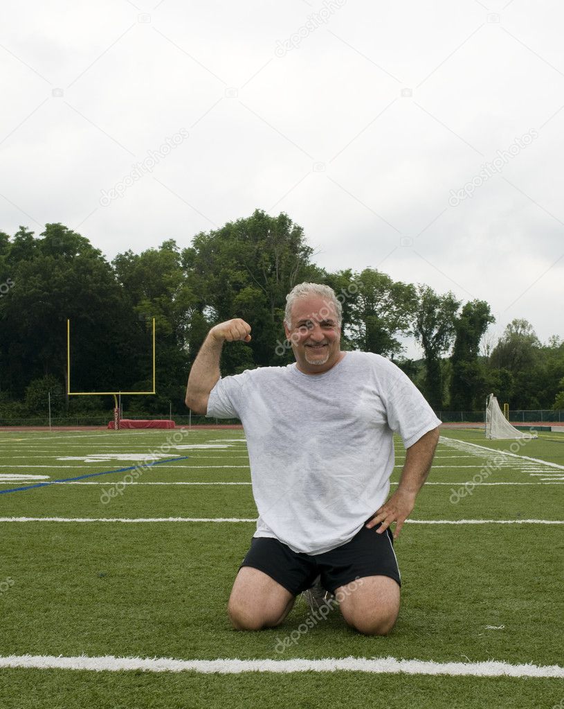 Middle age man stretching and exercising on sports field
