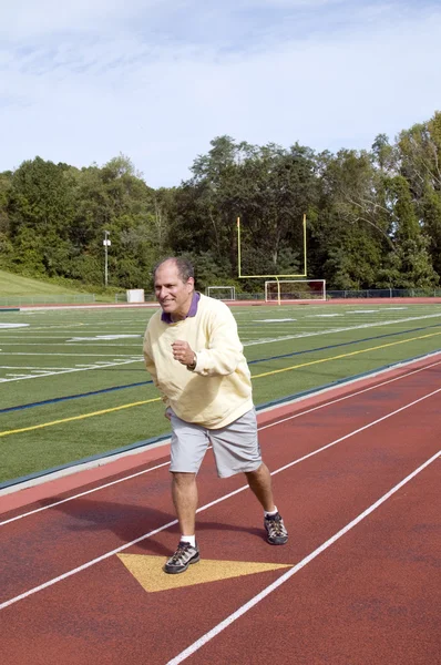 Uomo anziano di mezza età che si esercita correndo sul campo sportivo e correre — Foto Stock