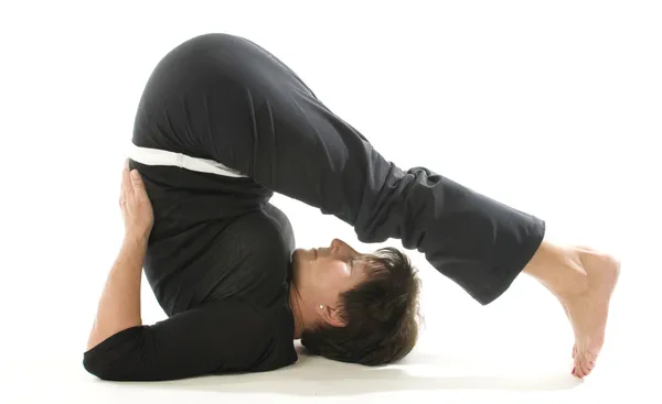 Middelbare leeftijd vrouw demonstreren yoga positie halasana de ploeg — Stockfoto