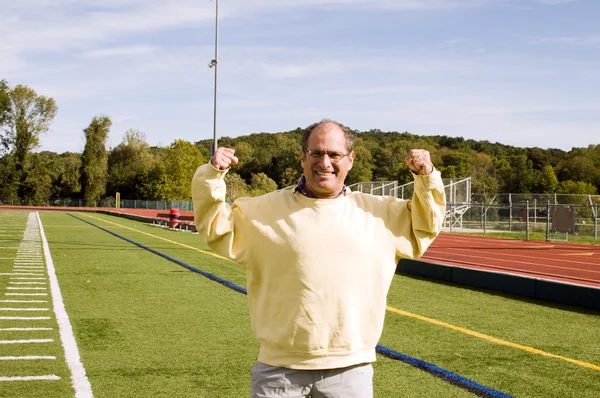 Hombre mayor de mediana edad estiramiento ejercicio en el campo de deportes —  Fotos de Stock