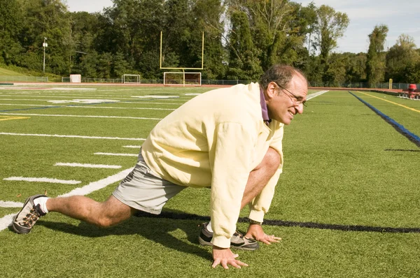 Middle age senior man stretching exercising on sports field — Stock Photo, Image
