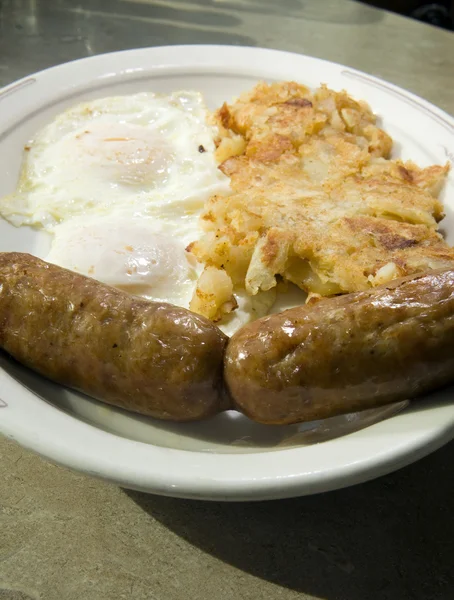 Fried eggs over easy pork sausages home fried potatoes breakfast — Stock Photo, Image