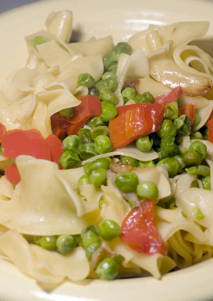 Noodles with green peas red pepper pieces and garlic butter — Stock Photo, Image
