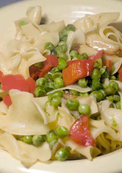 Macarrão com ervilhas verdes pedaços de pimenta vermelha e manteiga de alho — Fotografia de Stock