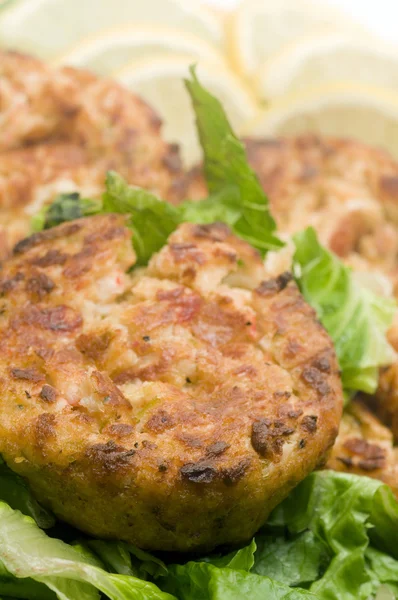 Lobster cakes bed of lettuce with lemon slice wedges — Stock Photo, Image