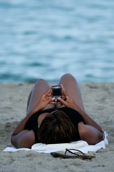 Woman texting on the beach — Stock Photo, Image