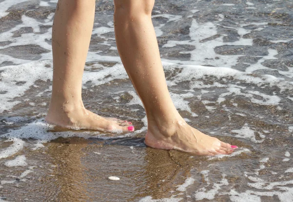 Woman with pink nail polish walking on the beach — Stock Photo, Image