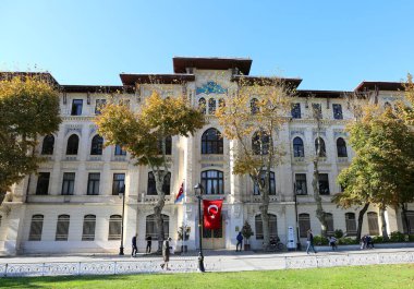 ISTANBUL,TURKEY-OCTOBER 30:People and Trees with Fall Colors in front of the Ottoman Ministry of Land Registry and Cadastre Building .October 30,2021 in Istanbul,Turkey