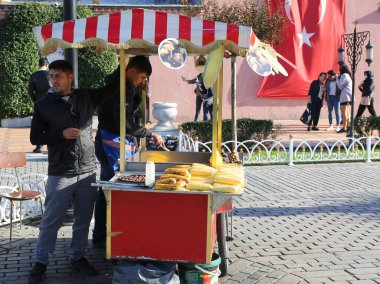 ISTANBUL,TURKEY-OCTOBER 30:Unidentified Guys selling Corn and Chestnuts  at Sultanahmet Square.October 30,2021 in Istanbul,Turkey