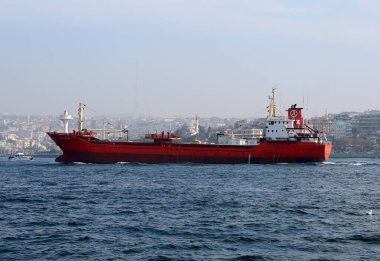 ISTANBUL,TURKEY-NOV 02: Red Cargo Ship Tanker and Buildings of Uskudar  from a Ferry. November  02,2021 in Istanbul, Turkey