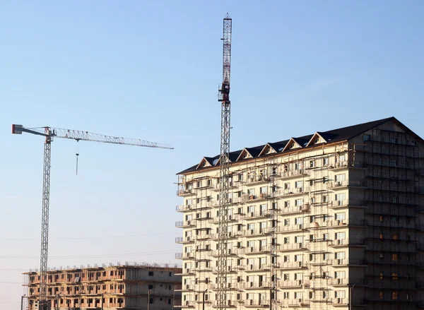 Cranes next to buildings covered in scaffolds — Stock Photo, Image