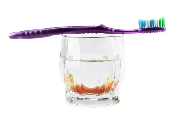 Dental health concept: partial denture inside glass with toothbrush on the top — Stock Photo, Image