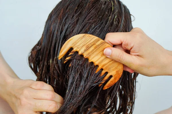 Woman in the shower combing hair treatment through hair.