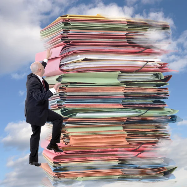 Geschäftsmann klettert auf Stapel endlosen Papiers — Stockfoto