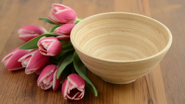 Poner huevos de Pascua en una taza con un montón de tulipanes alrededor . — Vídeos de Stock