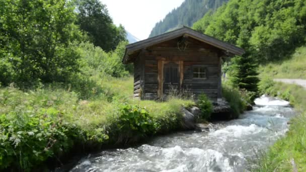 Hikers passing by a little alpine Hovel at stream water at Zillertal — Stock Video
