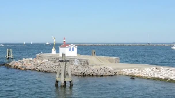 Small hut with a statue and alighthouse. The harbor entrance from Warnemunde in the Baltic Sea. — Stock Video