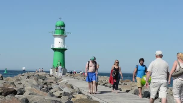 La gente camina hasta el faro de Warnemünde. un engranaje y un paseo en barco a motor desde el Mar Báltico hasta el puerto . — Vídeos de Stock