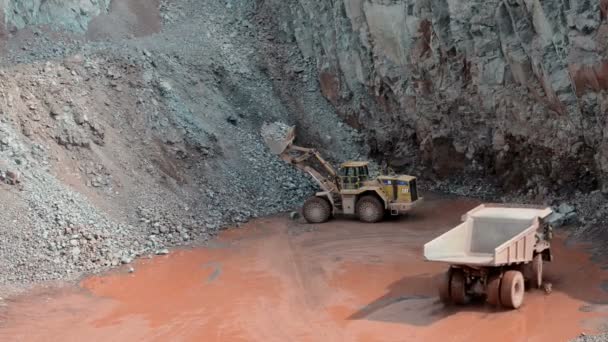 Earth mover ready to loading a dumper truck in a quarry — Stock Video