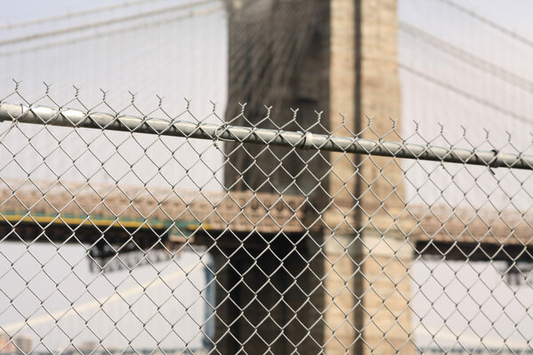 Barbed wire fence with brooklyn bridge in background
