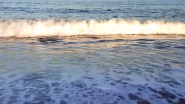 Ondas cayendo sobre la playa con reflejos de luz solar — Vídeo de stock