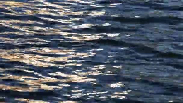 Waves lapping onto beach with sunlight reflections