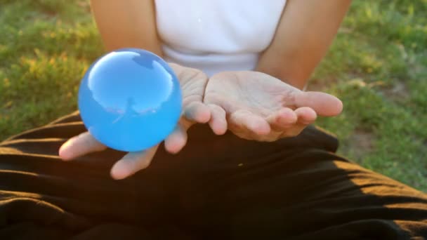 Une fille joue contact jongler avec une boule transparente en verre — Video