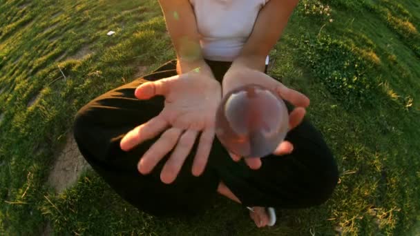 Une fille joue contact jongler avec une boule transparente en verre — Video