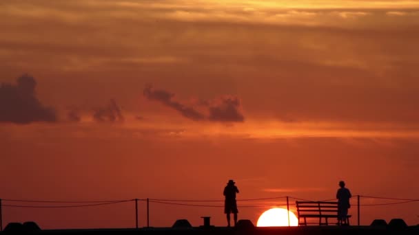 En un muelle en silueta mientras el sol se pone detrás de ellos, cozumel, México — Vídeo de stock