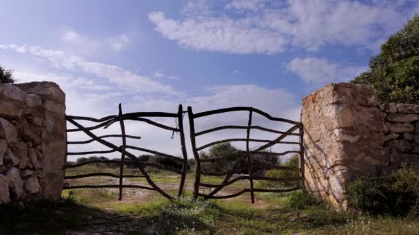 Vieux mur de pierre et portail de ferme avec nuages se déplaçant derrière 