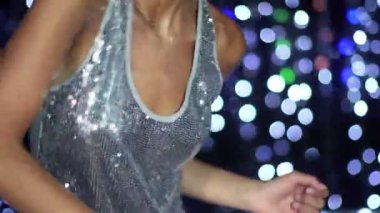 seksi bir kadın parlak bir disko arka plan ile dans ediyor.