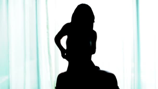 Silhouet van een mooie sexy meisje dansen in een suite hotel — Stockvideo