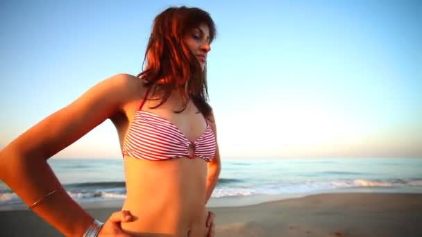 Menina bonita dança na praia em um biquíni ao nascer do sol — Vídeo de Stock