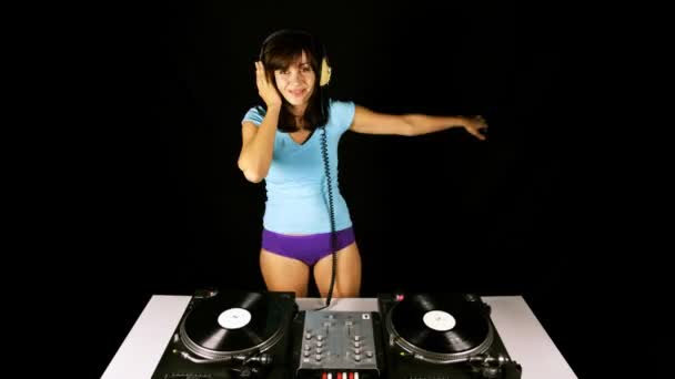 Hermosa joven hembra dj, detrás de las cubiertas en un club — Vídeo de stock