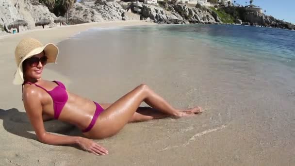Mooi meisje in een bikini sunbaths op het strand bij zonsopgang — Stockvideo