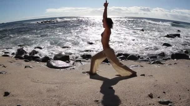 Молода жінка практикує йогу на пляжі на сході сонця — стокове відео
