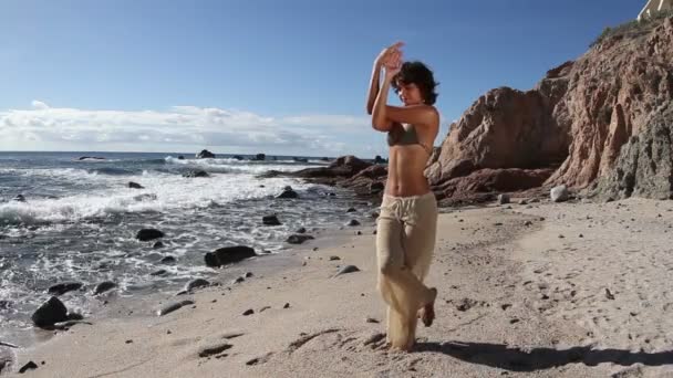 Νεαρή γυναίκα πρακτικές γιόγκα σε μια παραλία με την Ανατολή — Αρχείο Βίντεο