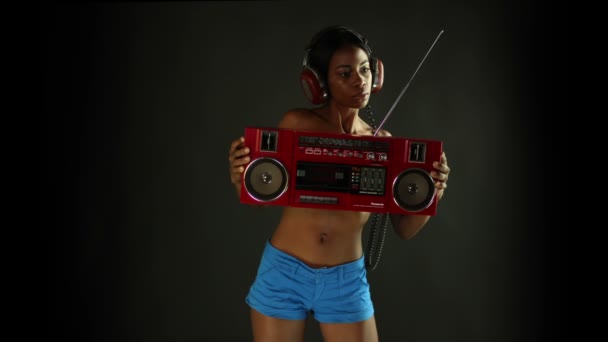 Szexi fiatal nő táncol, és jelent meg a gazdaság egy retro piros ghettoblaster — Stock videók