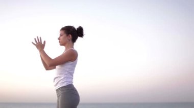 genç kadın yoga bir plajda güneş doğarken uygulamaları.
