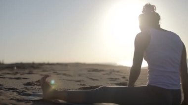 genç kadın yoga bir plajda güneş doğarken uygulamaları.