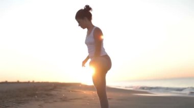 genç kadın yoga bir plajda güneş doğarken uygulamaları.