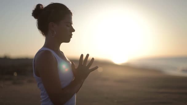 Молодая женщина практикует йогу на пляже на рассвете — стоковое видео
