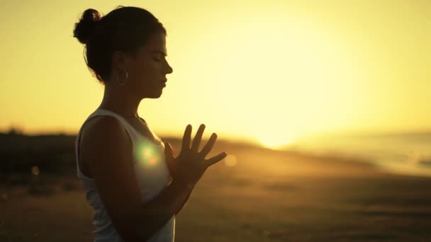 Молодая женщина практикует йогу на пляже на рассвете — стоковое видео